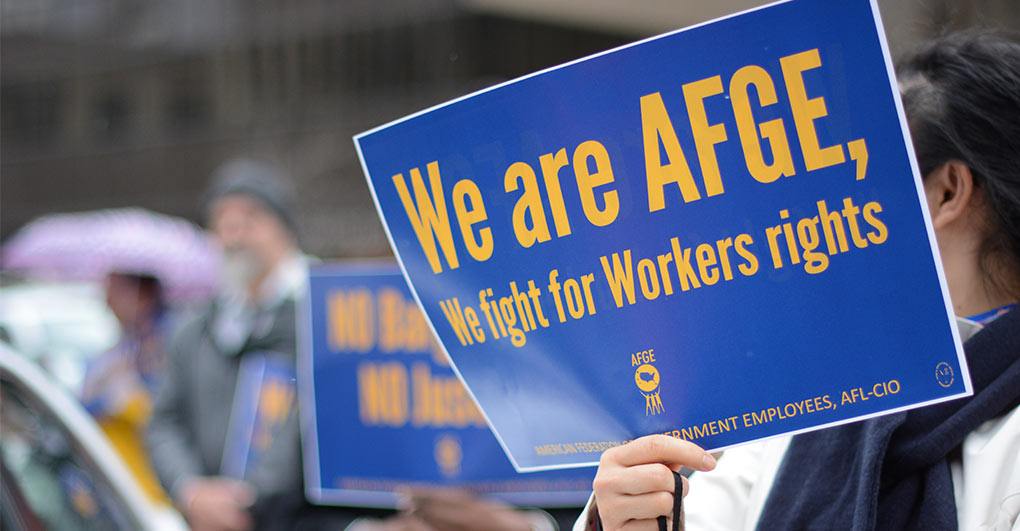 image of a person holding a sign that reads, "we are afge, we fight for workers rights"